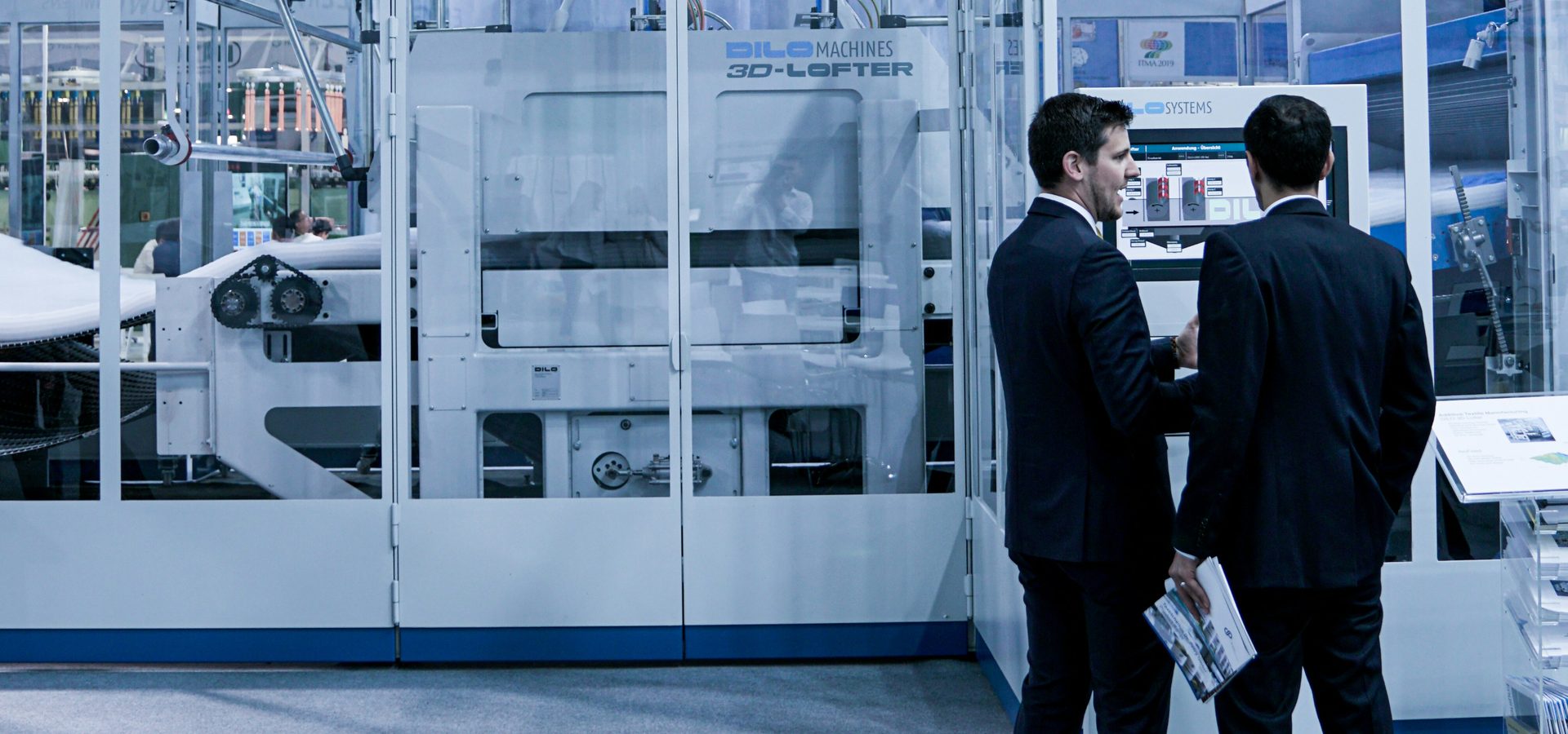 Two executives in suits in front of an automated production line